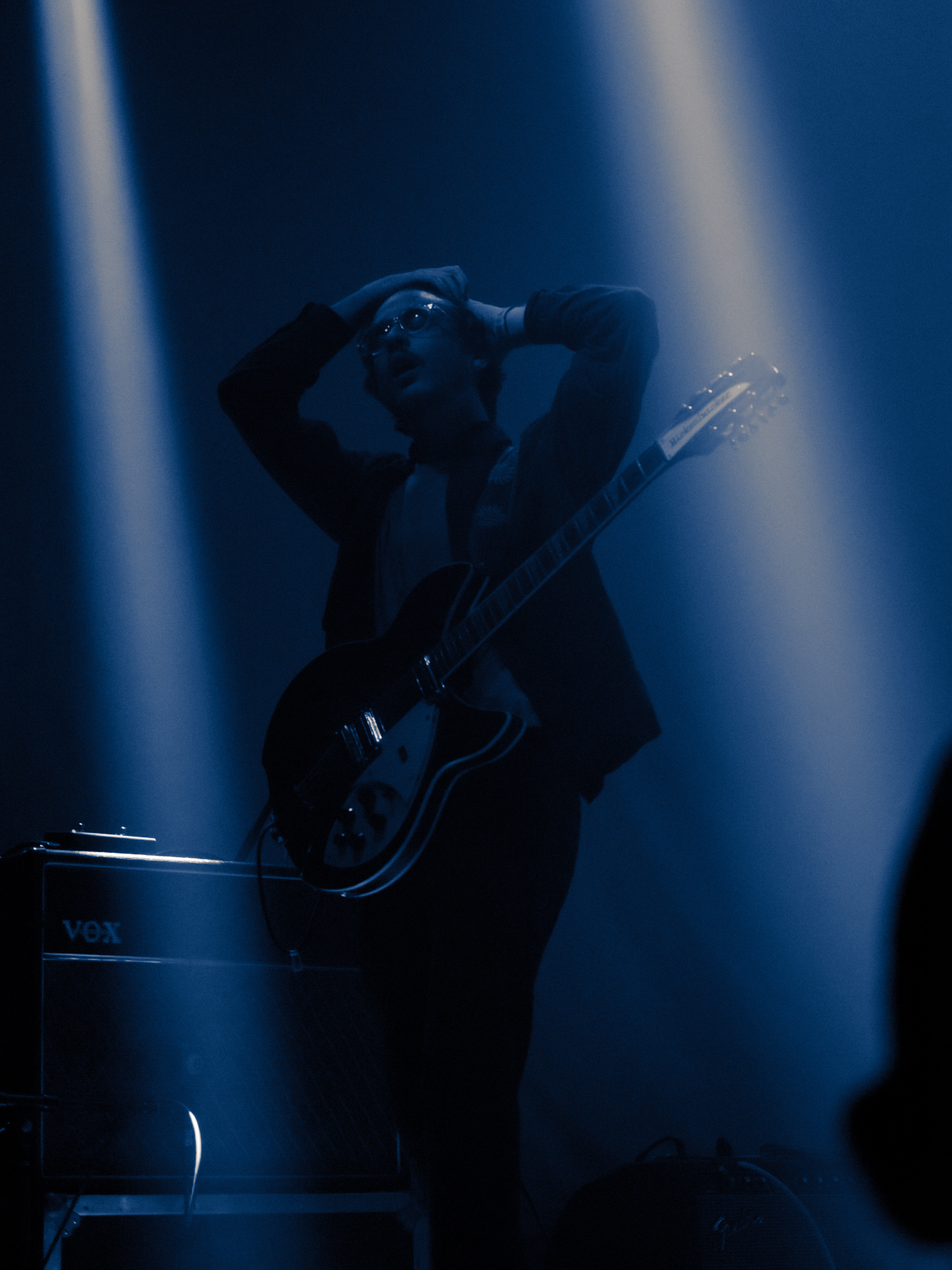 Trevor walks forward, arms above his head, brushing back his hair.