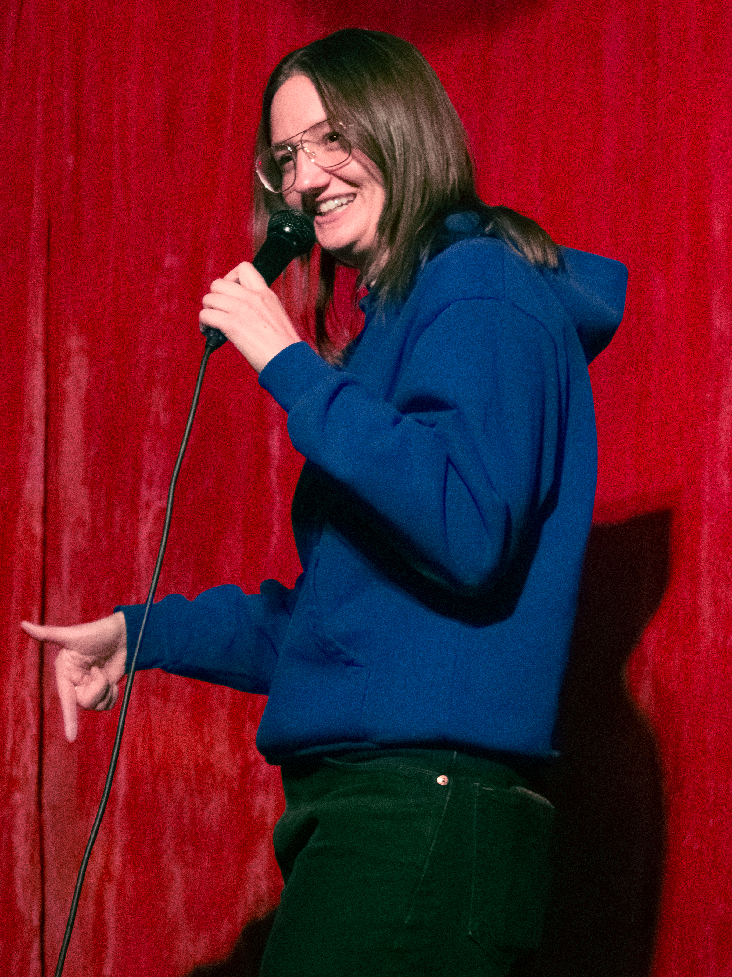 Allison O'Connor points at stage below her and smiles.