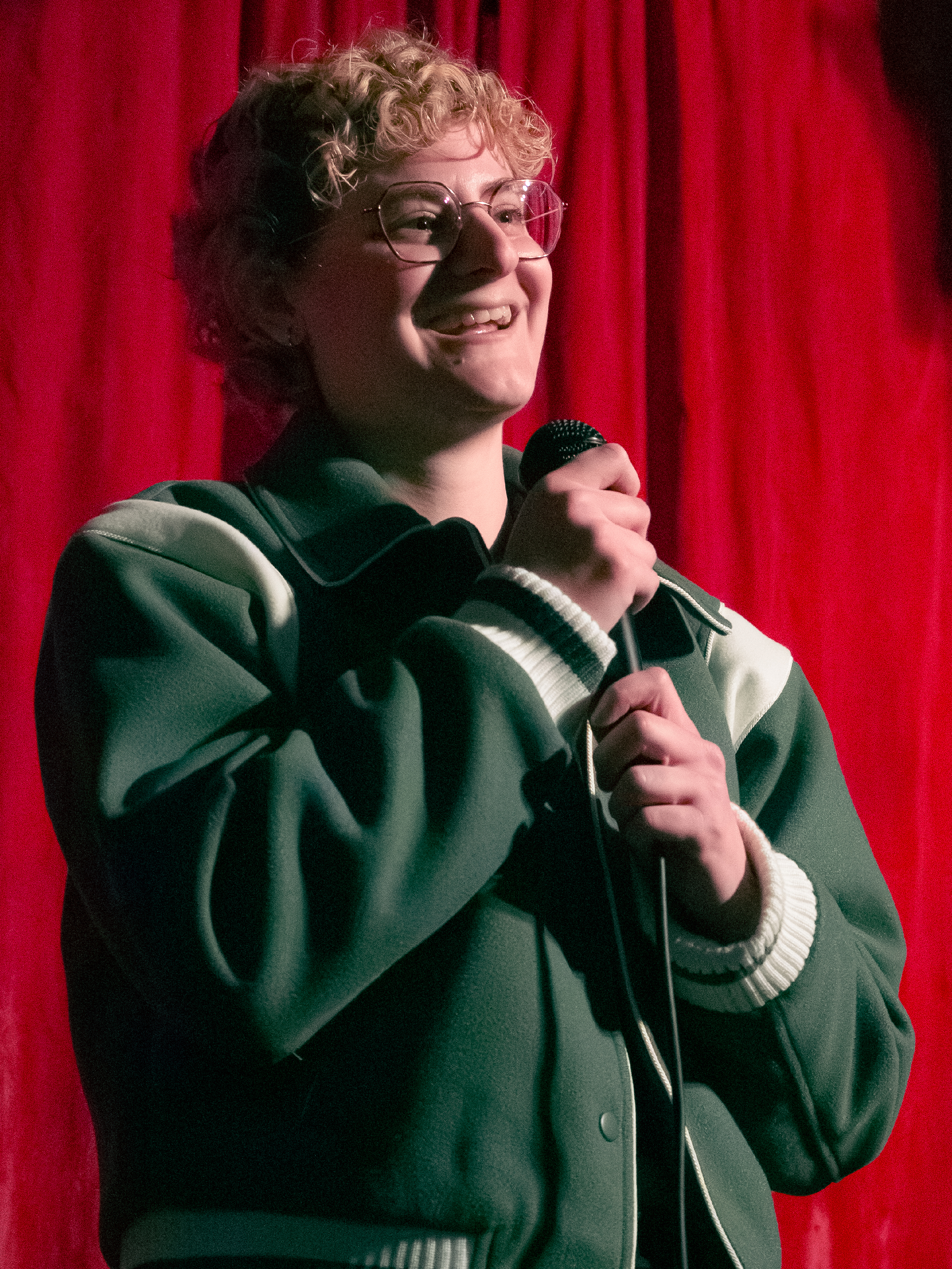 Erica Green tells a joke with both hands on the mic.