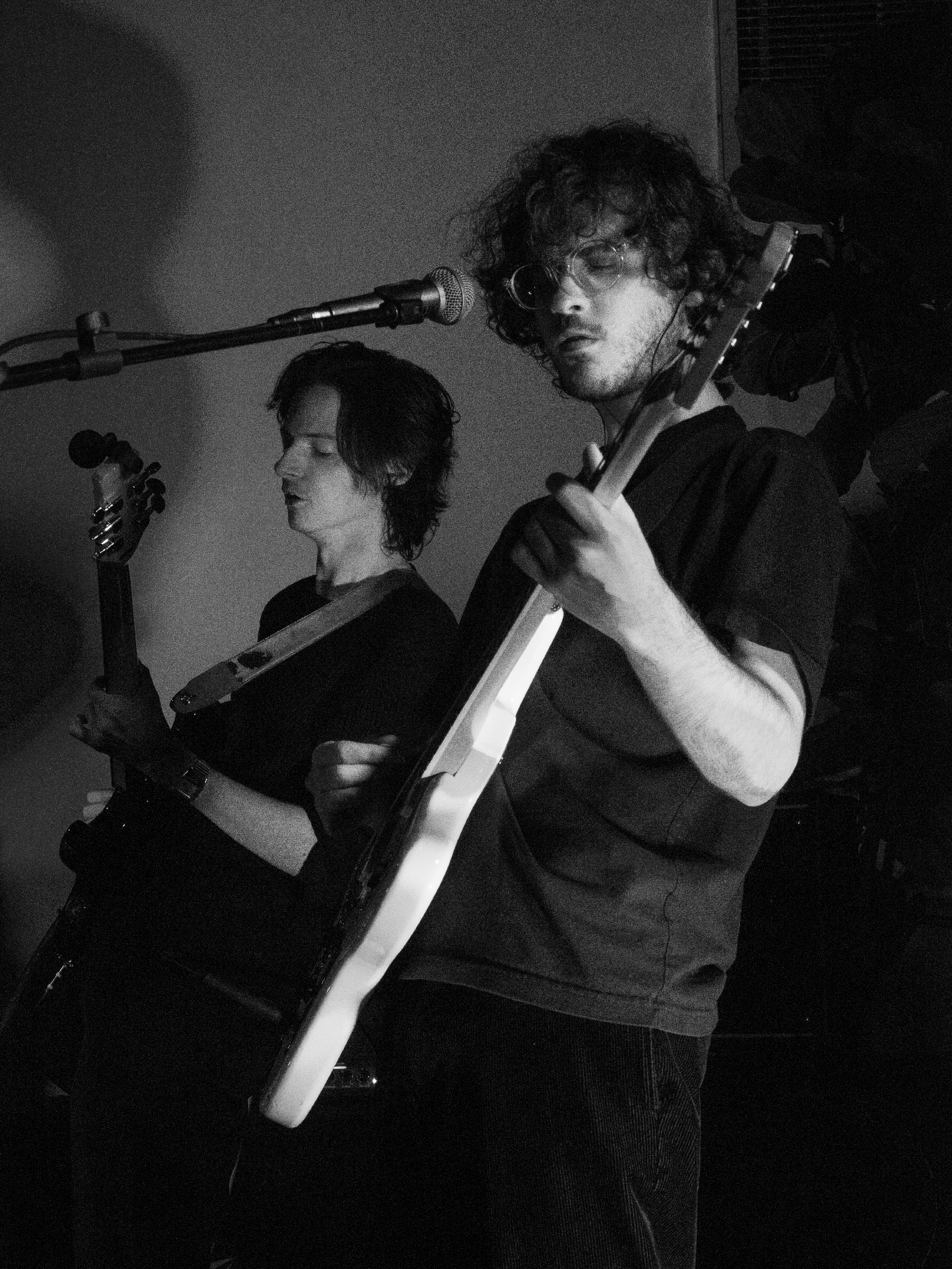 Ben plays guitar in the background, framed by Trevor playing guitar in the foreground.